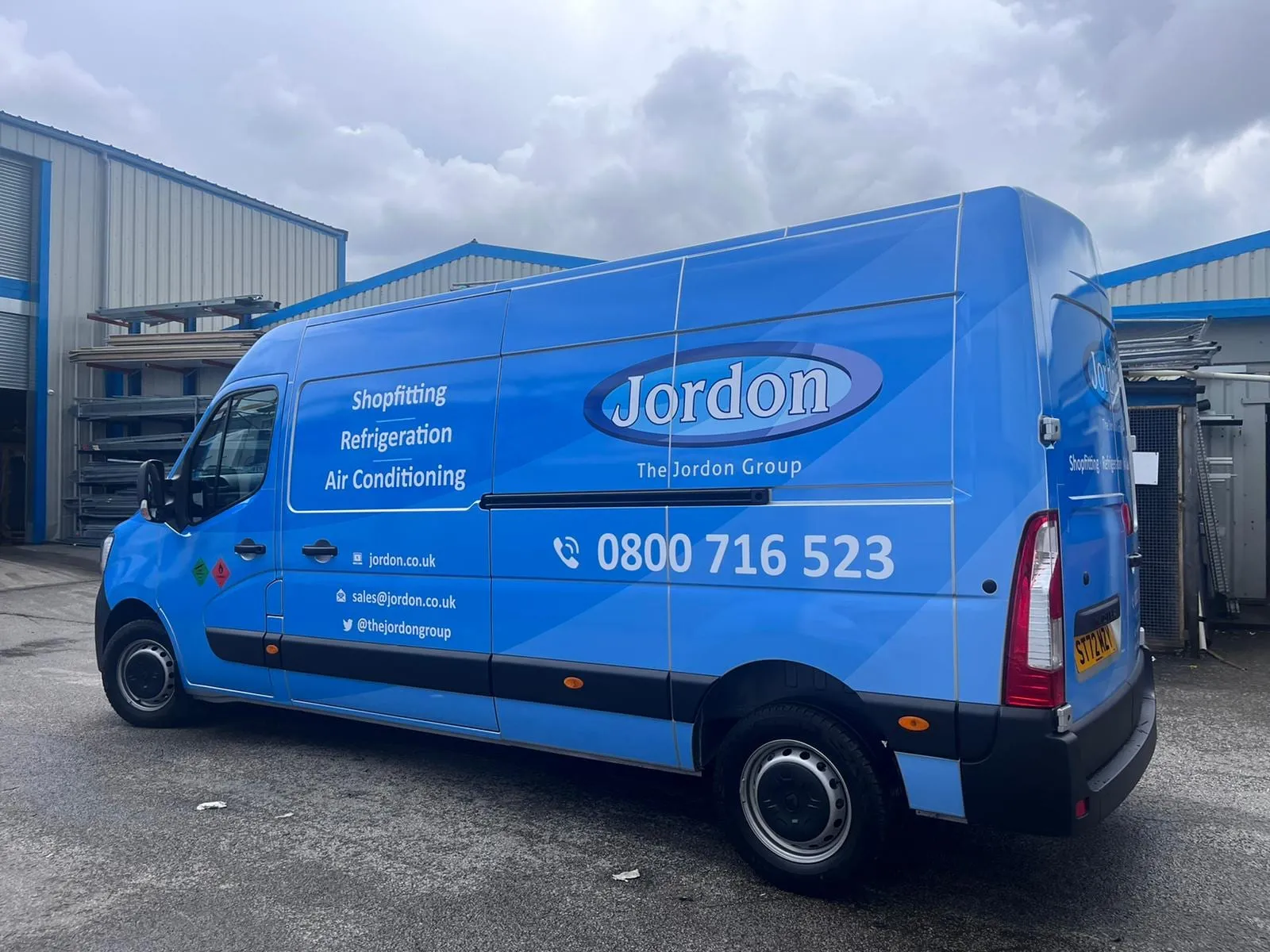 Blue van with business graphics across the side and rear doors