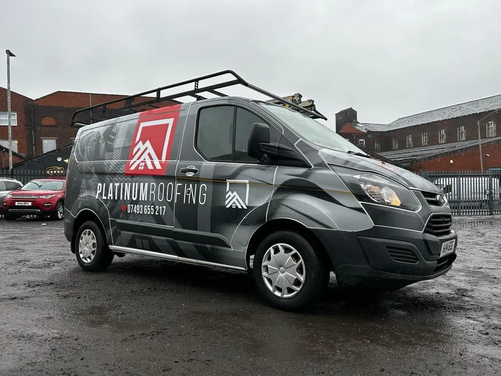 Dark grey van with a roof rack and a red and white logo on the side
